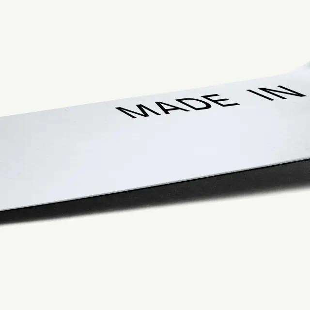 A close-up of a shiny metal surface displaying the phrase "MADE IN" in bold black letters.