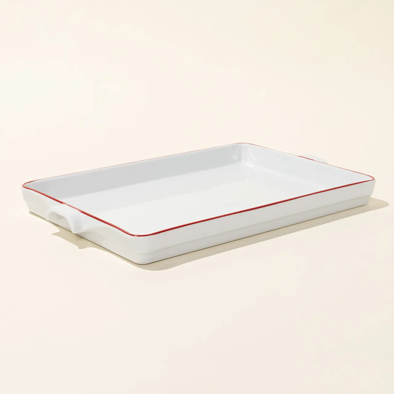 A white ceramic baking dish with red trim sits on a neutral background.