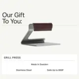 A sleek stainless steel grill press, featuring a leather handle, designed for high-temperature cooking up to 800°F and made in Sweden.