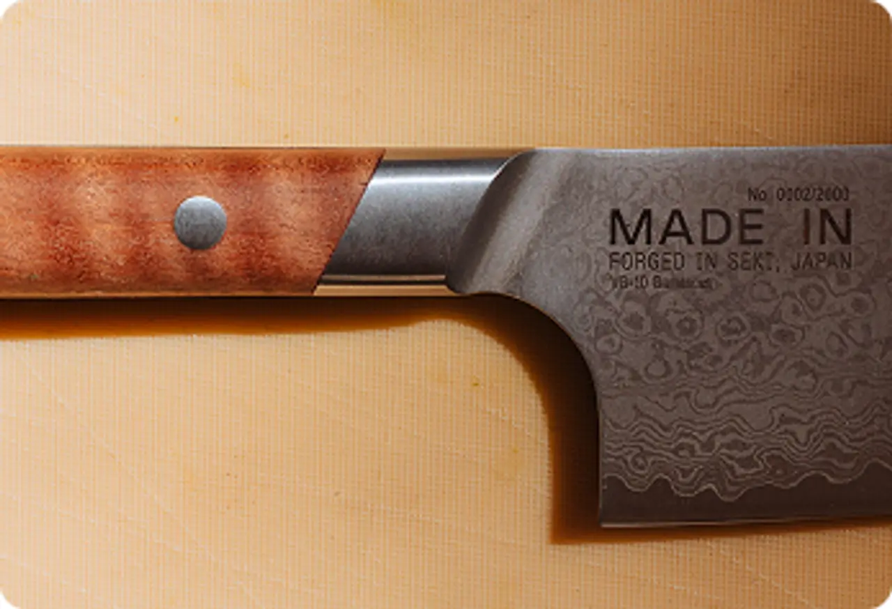 A close-up view of a high-quality chef's knife with a wooden handle, featuring the engraving "MADE IN Seki, Japan" on the blade.