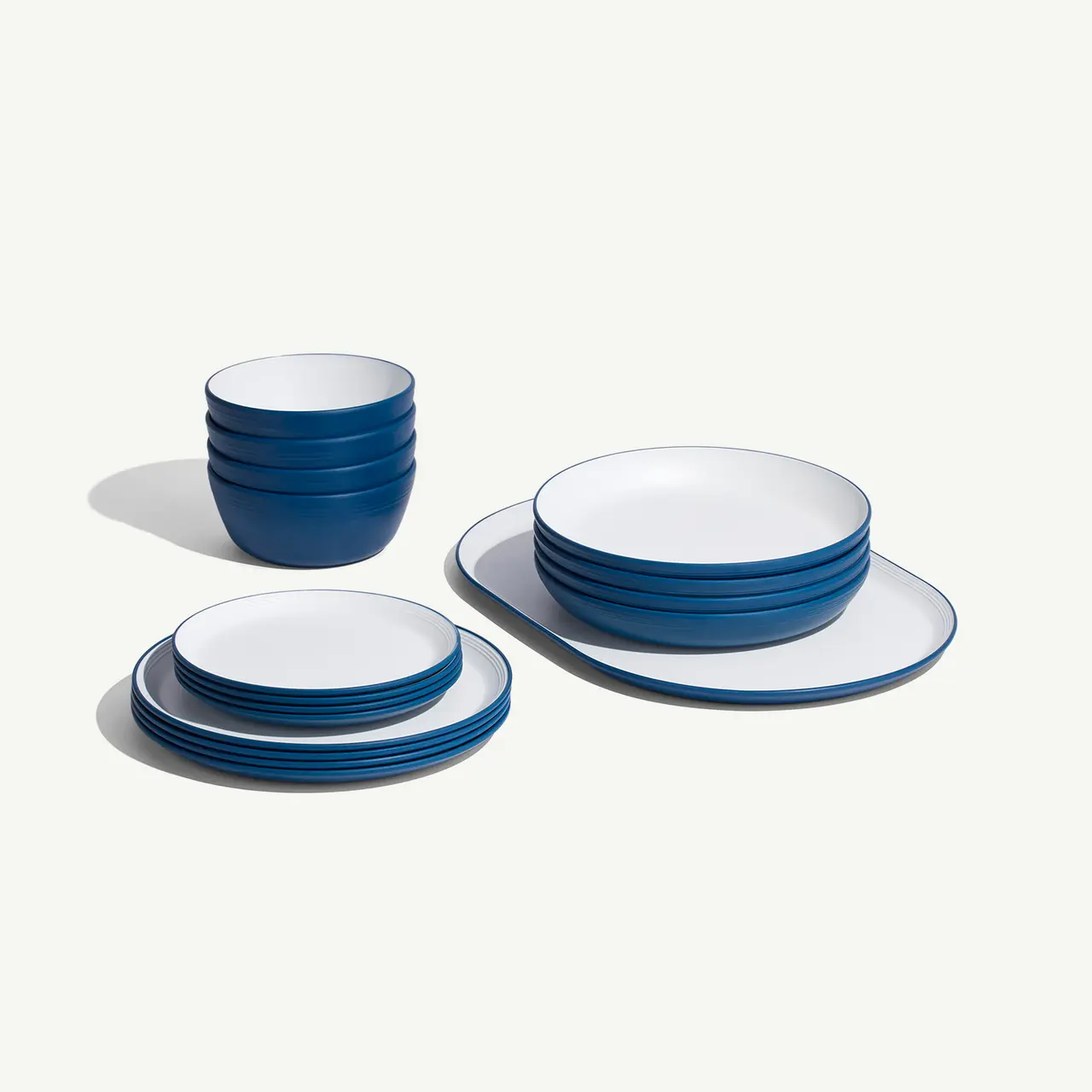 A set of blue-rimmed white dishes including stacked plates and bowls is neatly organized on a light surface.