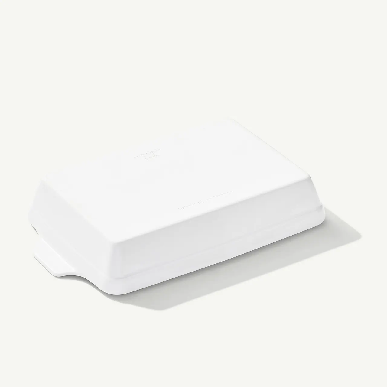 A sleek white wireless router with minimalistic design sits on a plain surface.