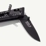 A sleek black folding knife features a carbon fiber handle and a stainless steel blade marked with "MADE IN."