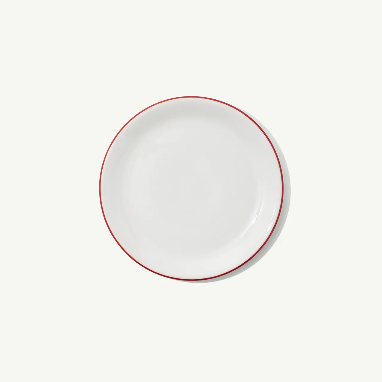 A white round plate with a red rim on a plain background.