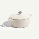 A round, white enameled cast iron Dutch oven with a metal handle on the lid.