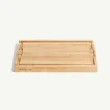 A rectangular bamboo cutting board with a smooth surface and a carved groove along the edges.