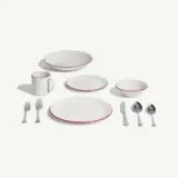 A set of white dinnerware with red trim, including plates, bowls, a mug, and cutlery arranged neatly on a light background.