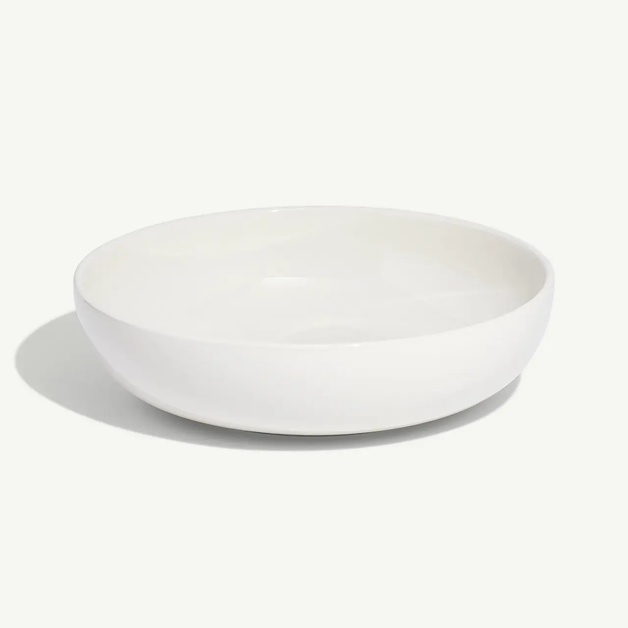 A plain white, round, ceramic bowl is centered on a light background.