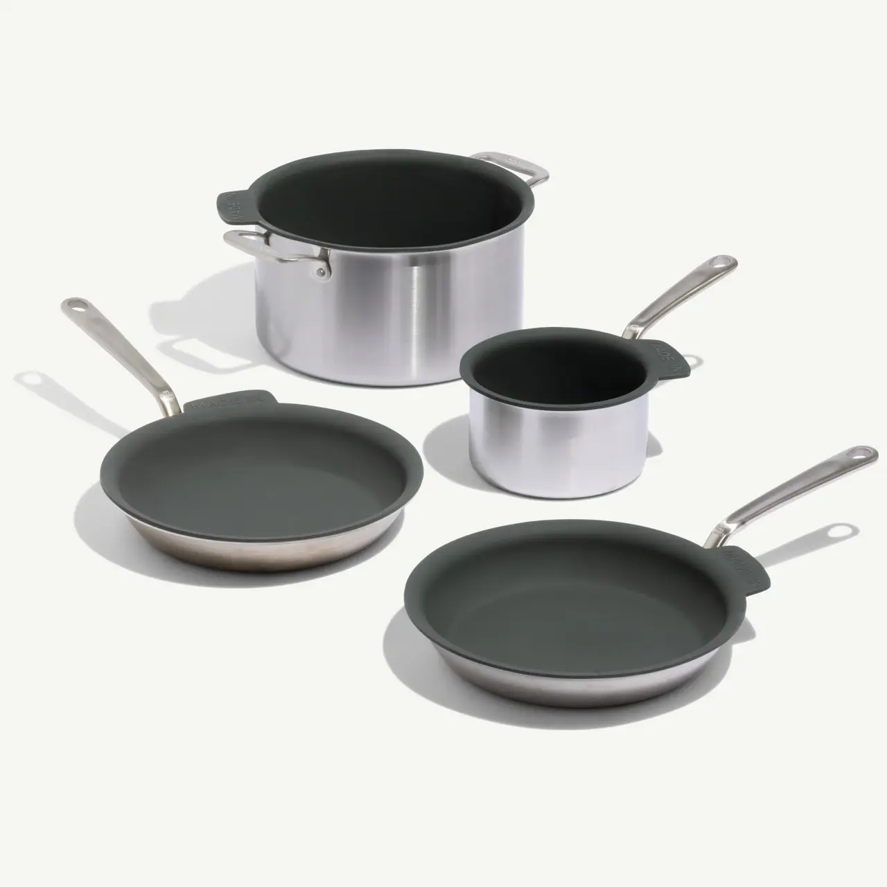 Four pieces of cookware, including two frying pans, a saucepan, and a pot, featuring a sleek silver and dark green design.