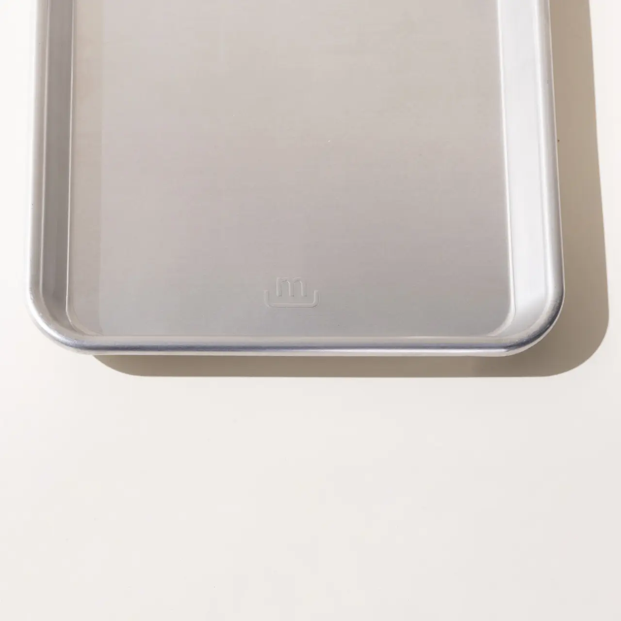 A translucent plastic lid with a frosted appearance and embossed with the letters "MU" placed on a neutral surface.