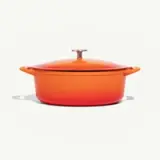 A vibrant orange Dutch oven with a lid on a neutral background.