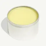 A tin filled with solid yellow balm sits against a white background.