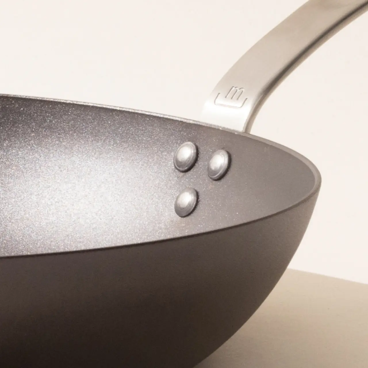 A close-up of a non-stick frying pan focusing on its interior surface and the rivets attaching the handle.