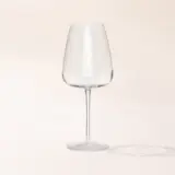 An empty wine glass on a plain background casting a soft shadow.