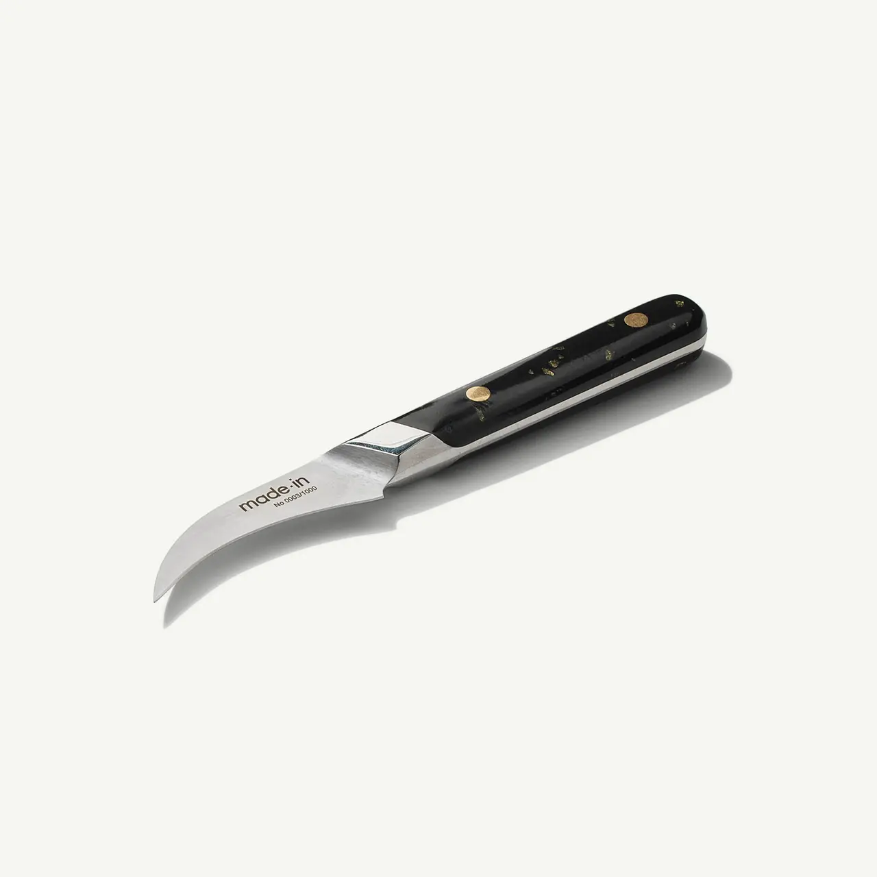 A folding pocket knife with a curved blade and black handle with metal and brass accents lies on a white background.