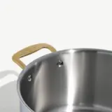 A stainless steel pot with a gold-colored handle is shown against a light background.