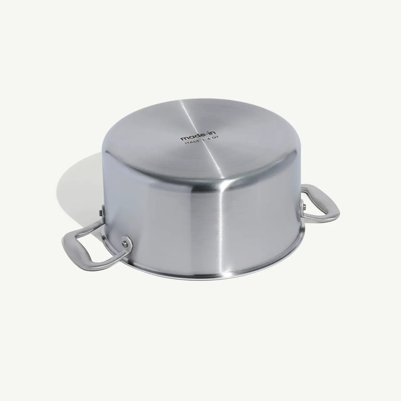 A stainless steel pot with two handles and a lid, isolated on a light background.