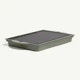 A green serving tray with a smooth, dark surface and built-in handles for easy carrying.