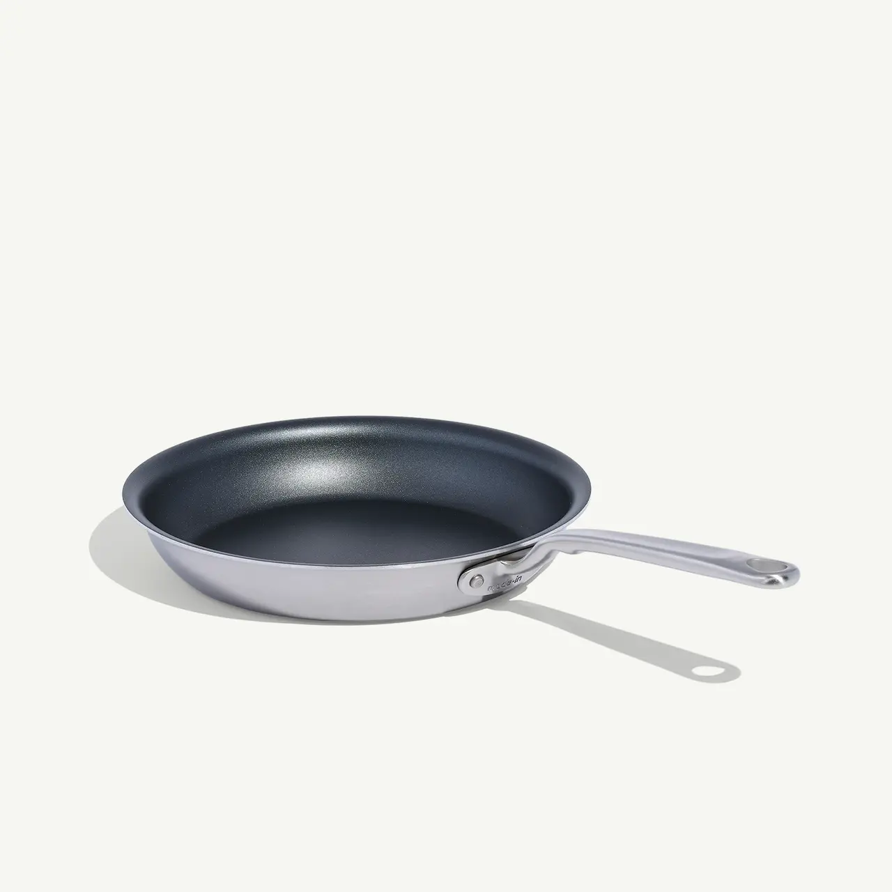 A non-stick frying pan with a stainless steel handle sits isolated on a white background.
