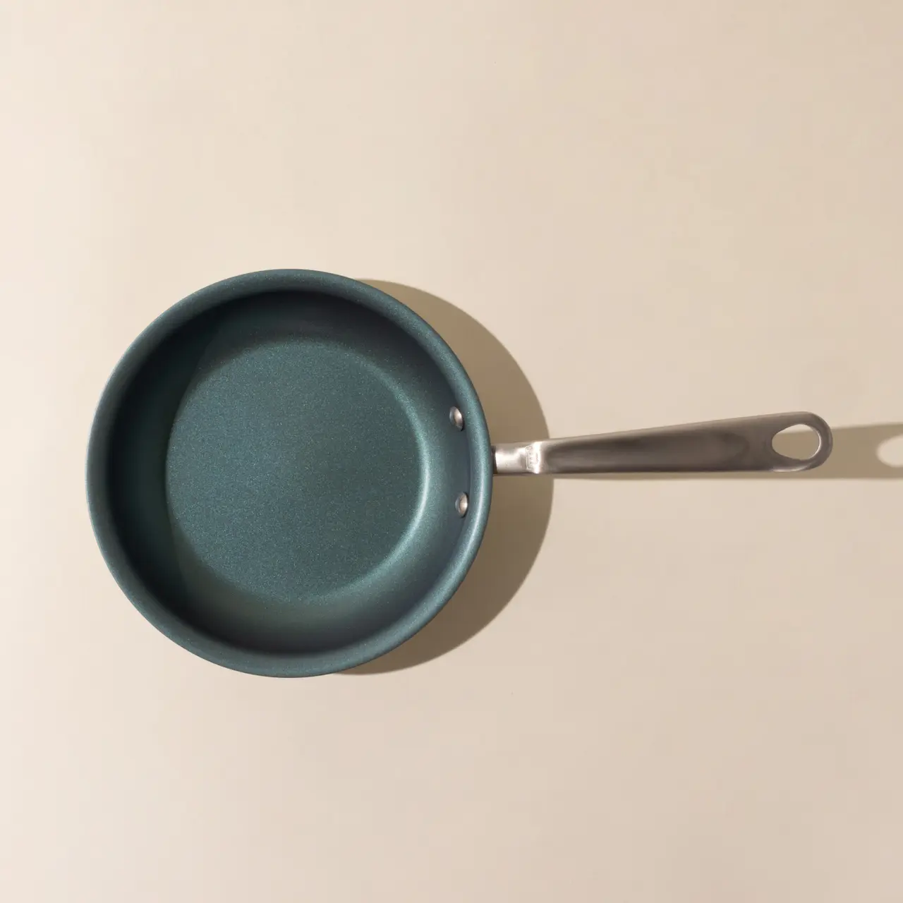 Non-stick frying pan with a silver handle set against a simple, neutral background.