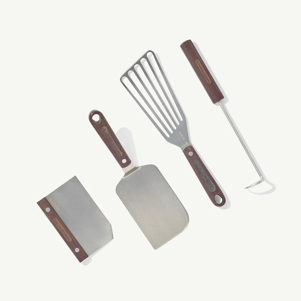 A set of three kitchen utensils with wooden handles, including a spatula, flipper, and fork on a plain background.