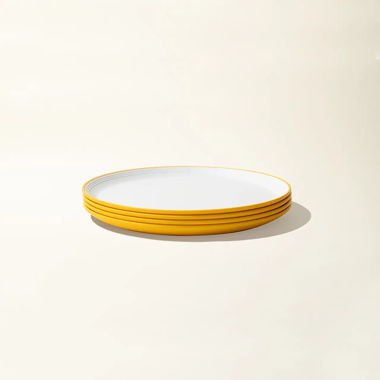 A stack of simple yellow-rimmed white plates on a light background.