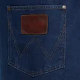 A close-up view of the back pocket of a pair of jeans, featuring a leather tag that reads "Wrangler MADE IN."