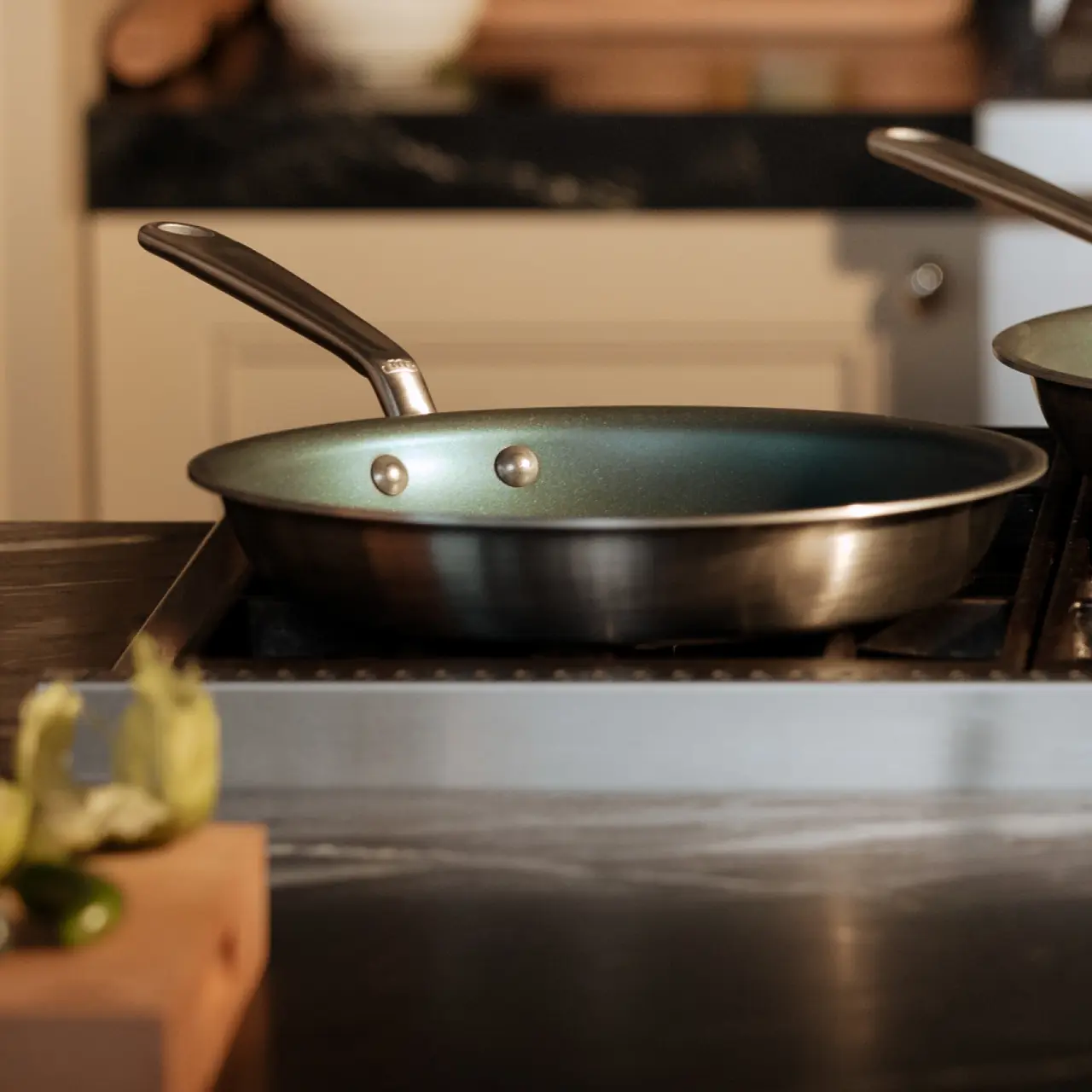 A frying pan with two rivets forming "eyes" on its inner surface, resembling a face, is placed on a stove in a home kitchen.