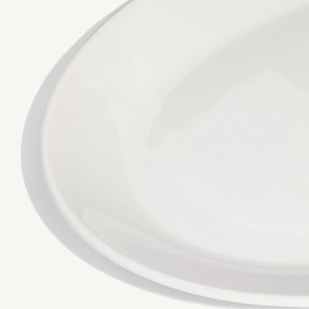 A clean, white ceramic plate angled slightly on a white background.