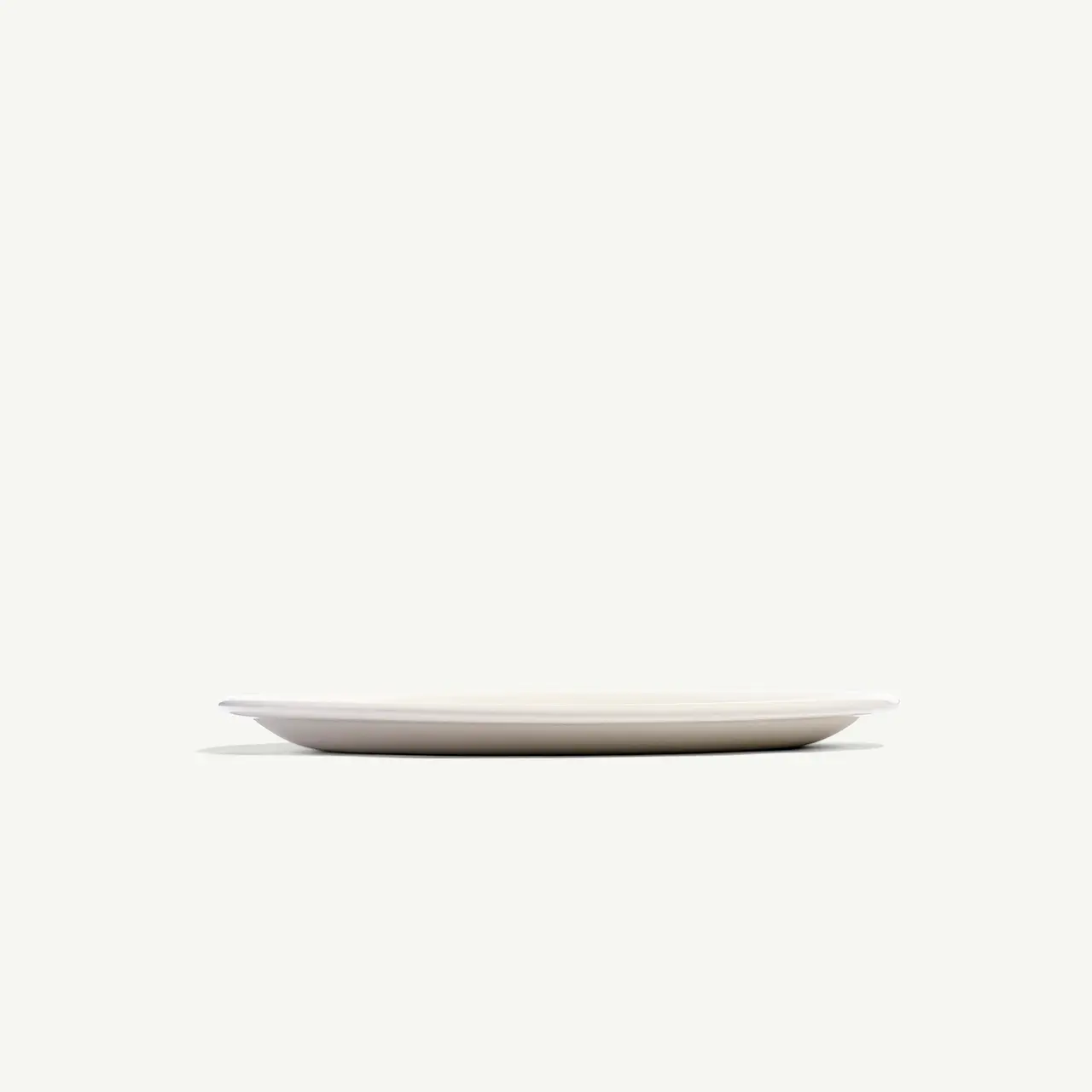 A simple empty white plate is centered on a plain light background.