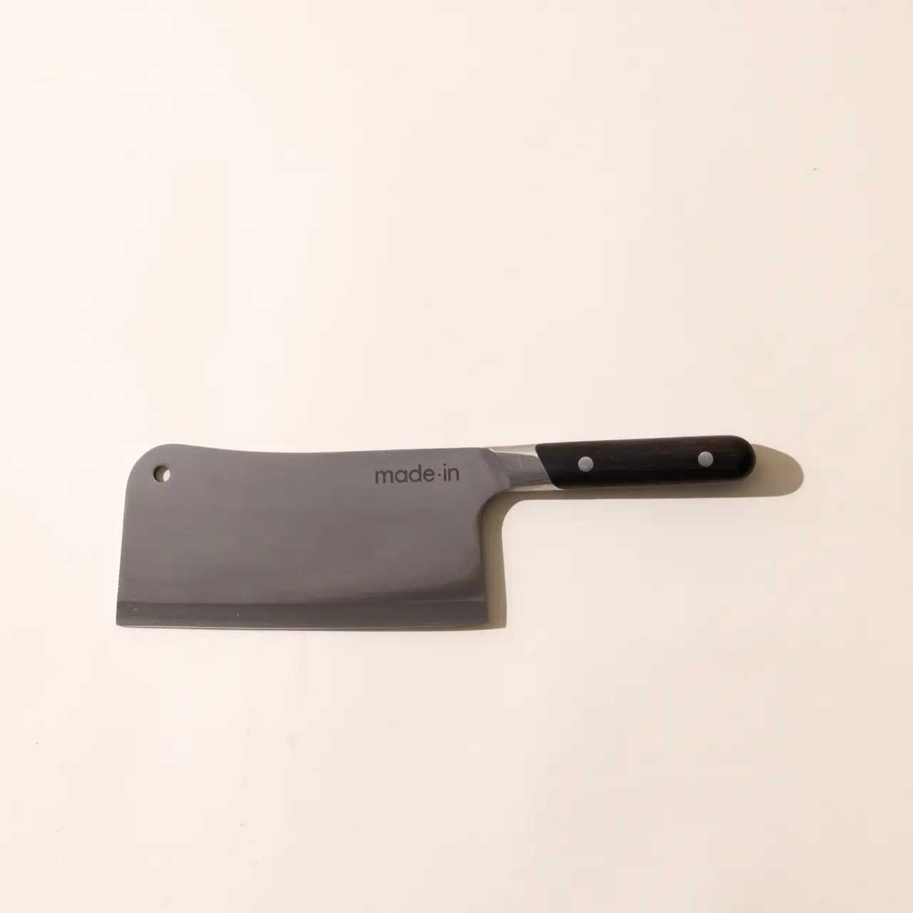 A cleaver with a black handle labeled "made.in" on a plain background.