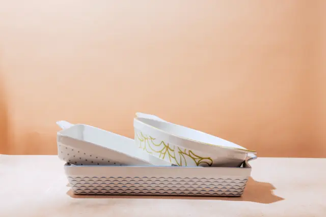 A pair of white casual slip-on shoes with a decorative pattern is resting on a beige surface against a peach background.
