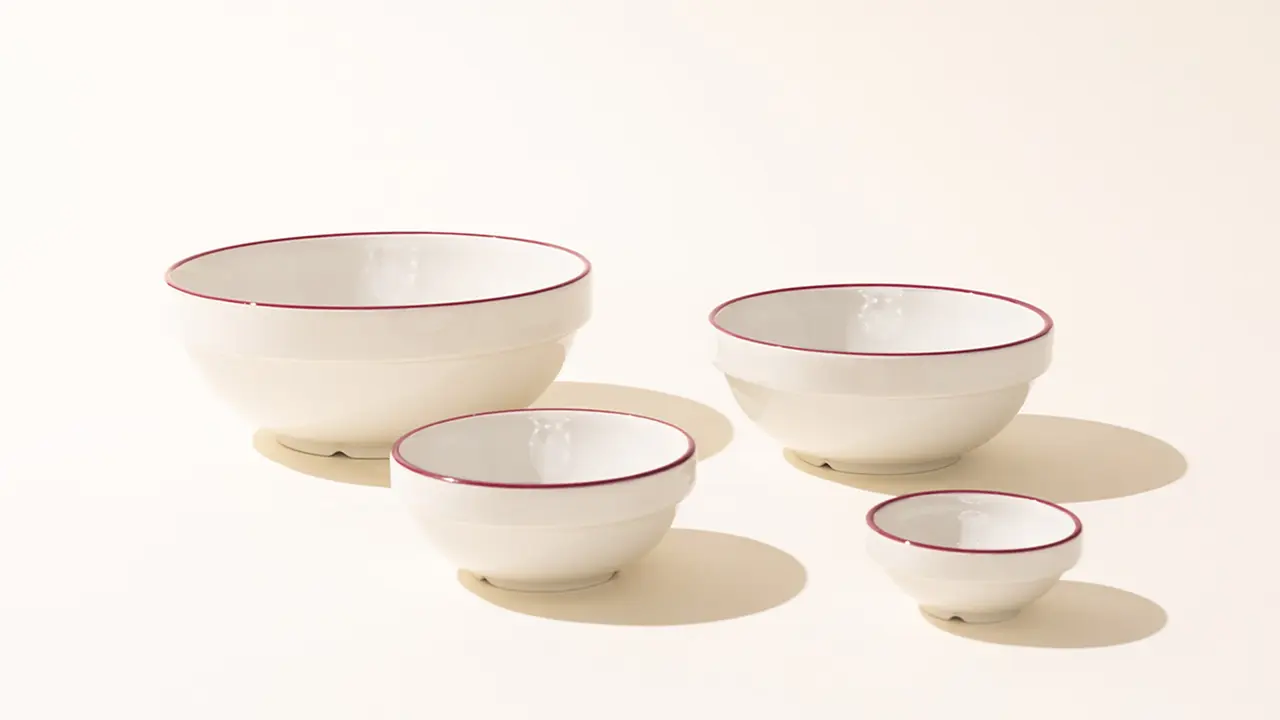 Four white bowls with red rims are arranged by size on a light background.