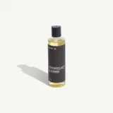 A bottle of CeramicClad™ cleaner featuring a sleek black label and gold liquid.