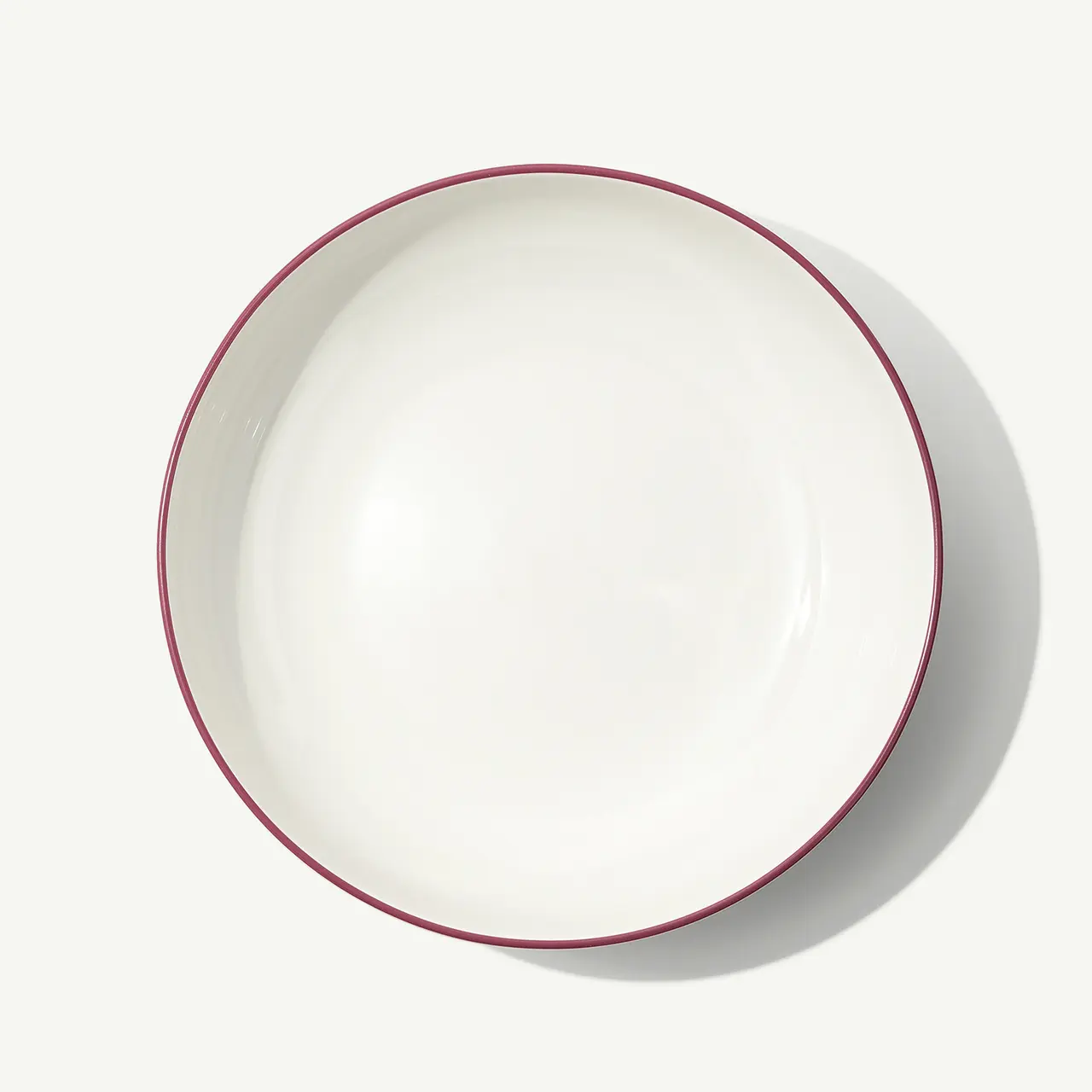 A white bowl with a red rim is centered on a plain background.