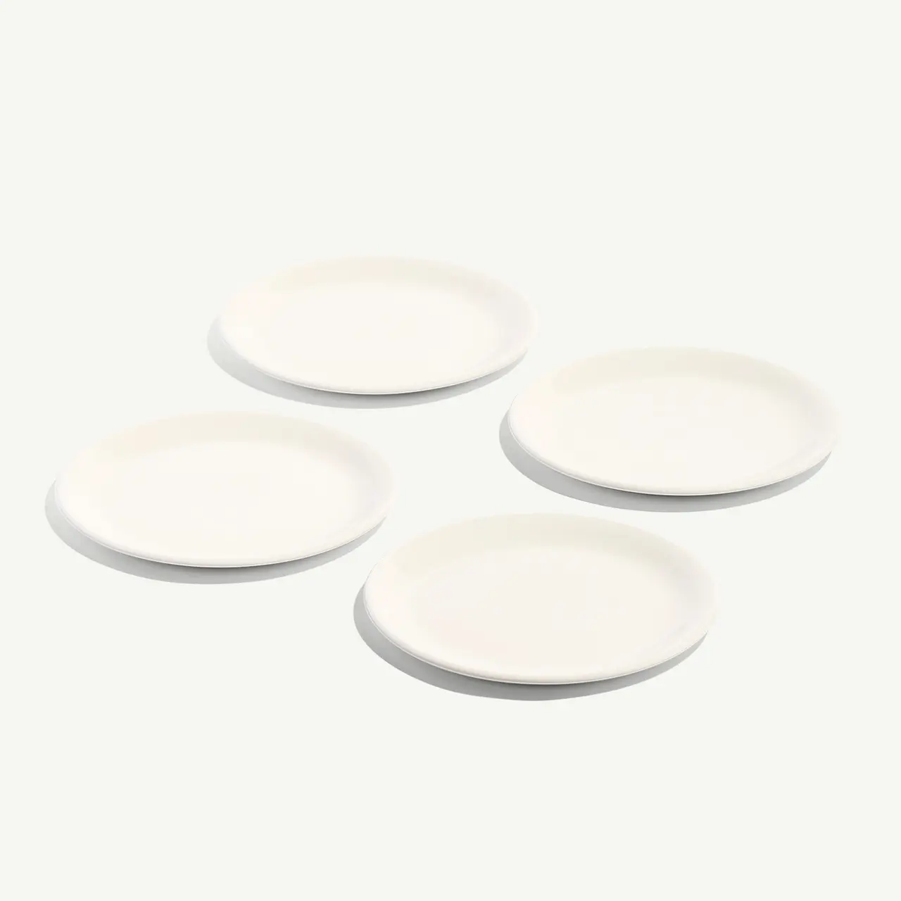 Four white round plates are arranged on a light background.
