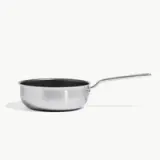 A stainless steel frying pan with a long handle is isolated on a light background.