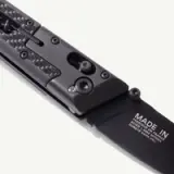 A sleek, black knife featuring carbon fiber elements and a visible engraved inscription indicating its made-in-France origin.