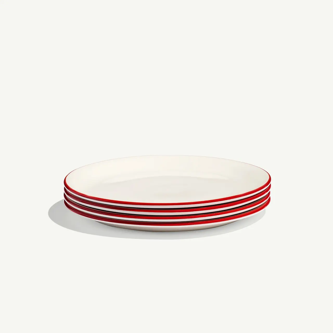 A stack of white plates with a single red stripe along the edge on a plain background.