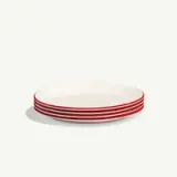 A stack of white plates with a single red stripe along the edge on a plain background.