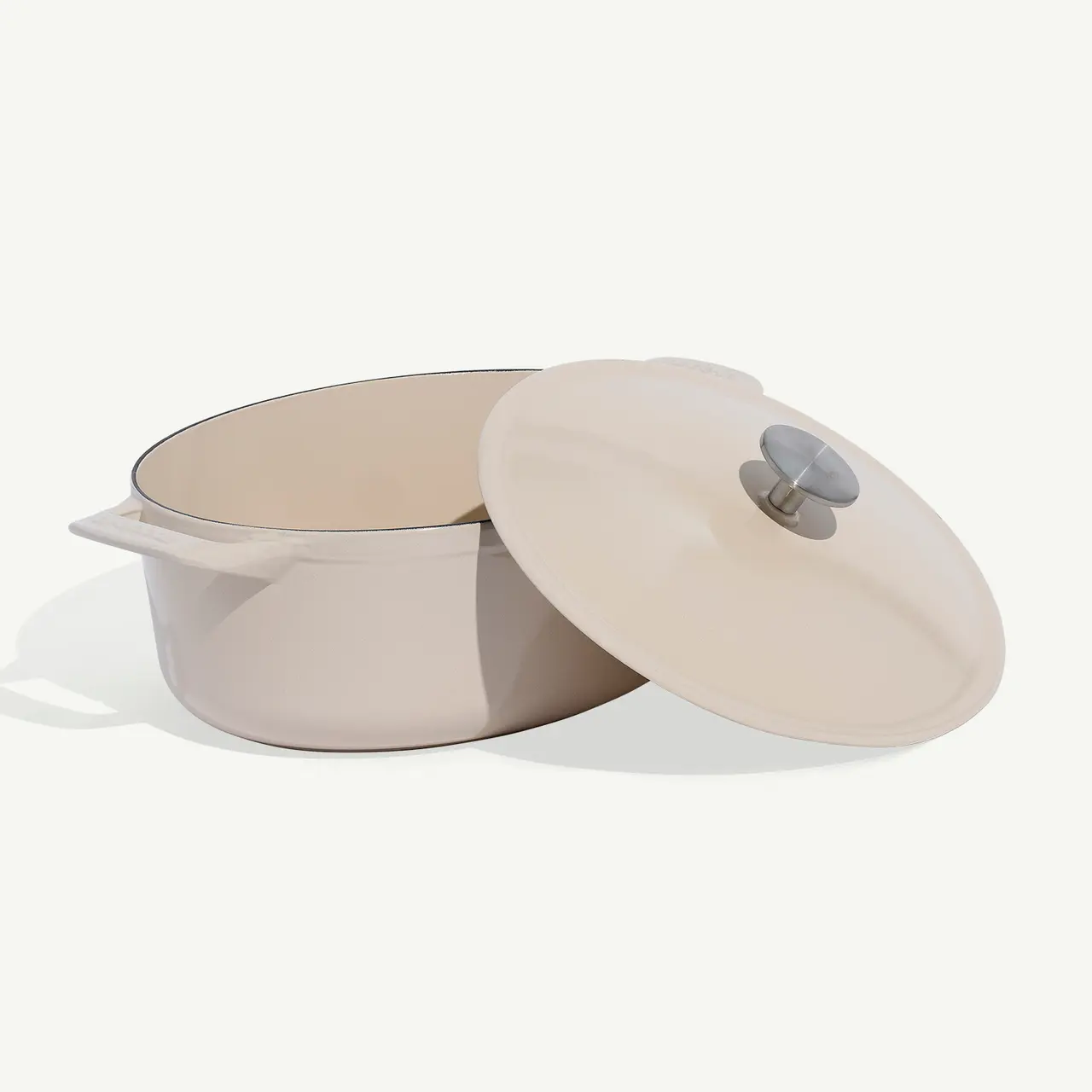 A beige Dutch oven with its lid slightly askew, set against a white background.