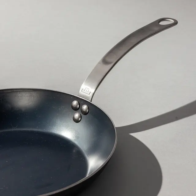 Carbon steel frying pan on grey background