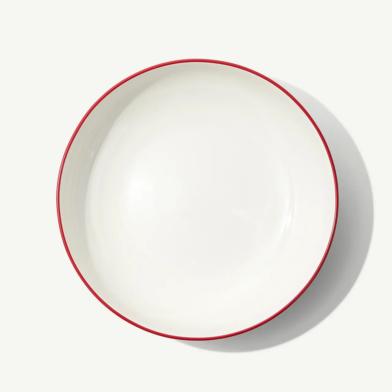 A white, empty bowl with a red rim is centered on a plain background.