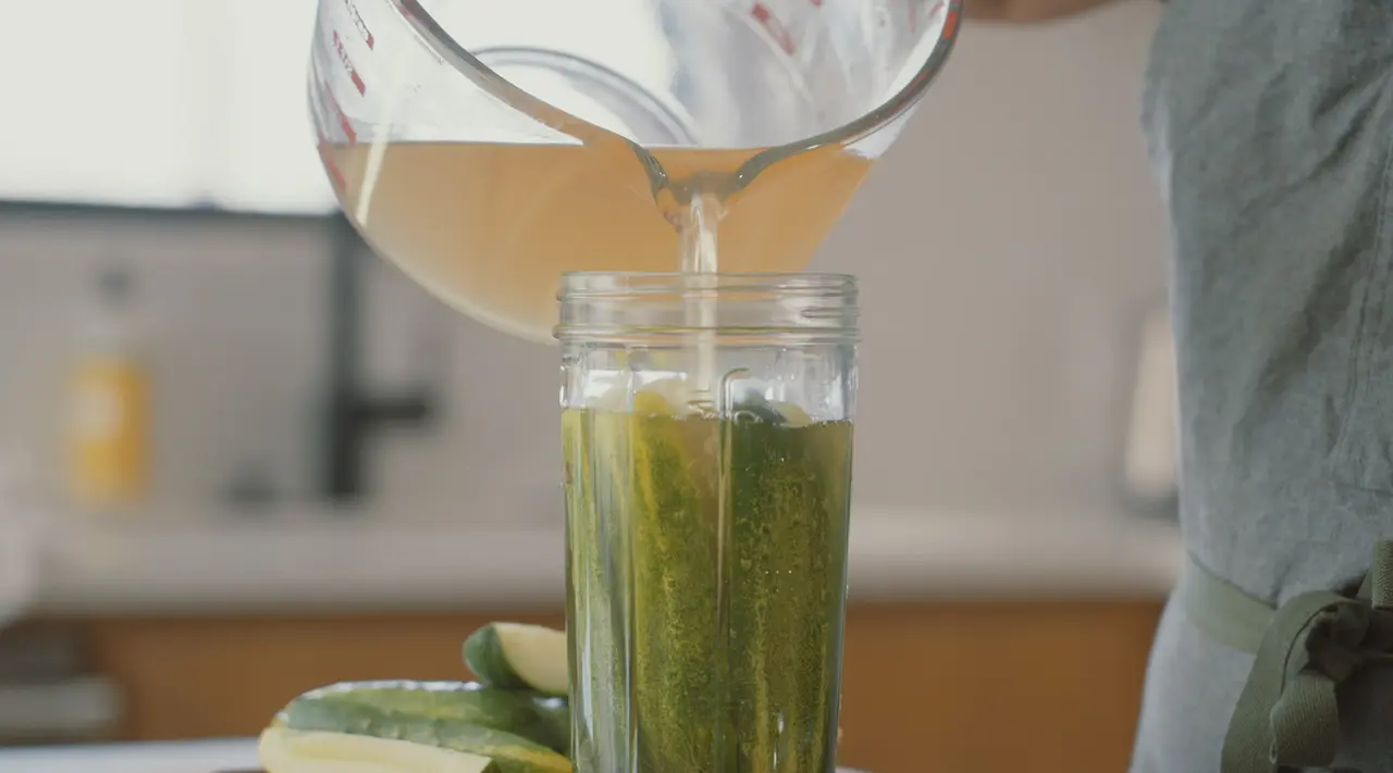 Liquid is poured into a jar filled with cucumbers to make pickles.