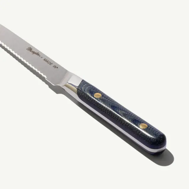 A serrated knife with a blue handle and silver accents, featuring the label "Made IN."