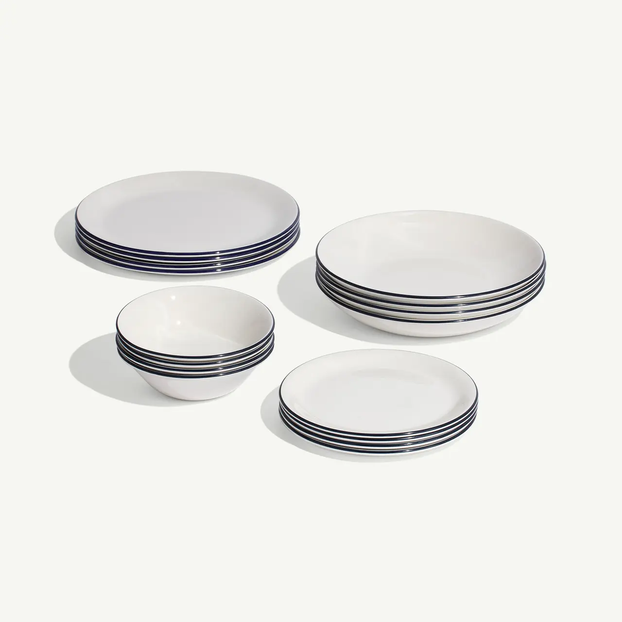 A set of white dishes with blue trim, including plates and bowls, arranged neatly on a light background.