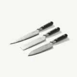 Three chef's knives with black handles are arranged on a light background, displaying their various sizes and blade textures.