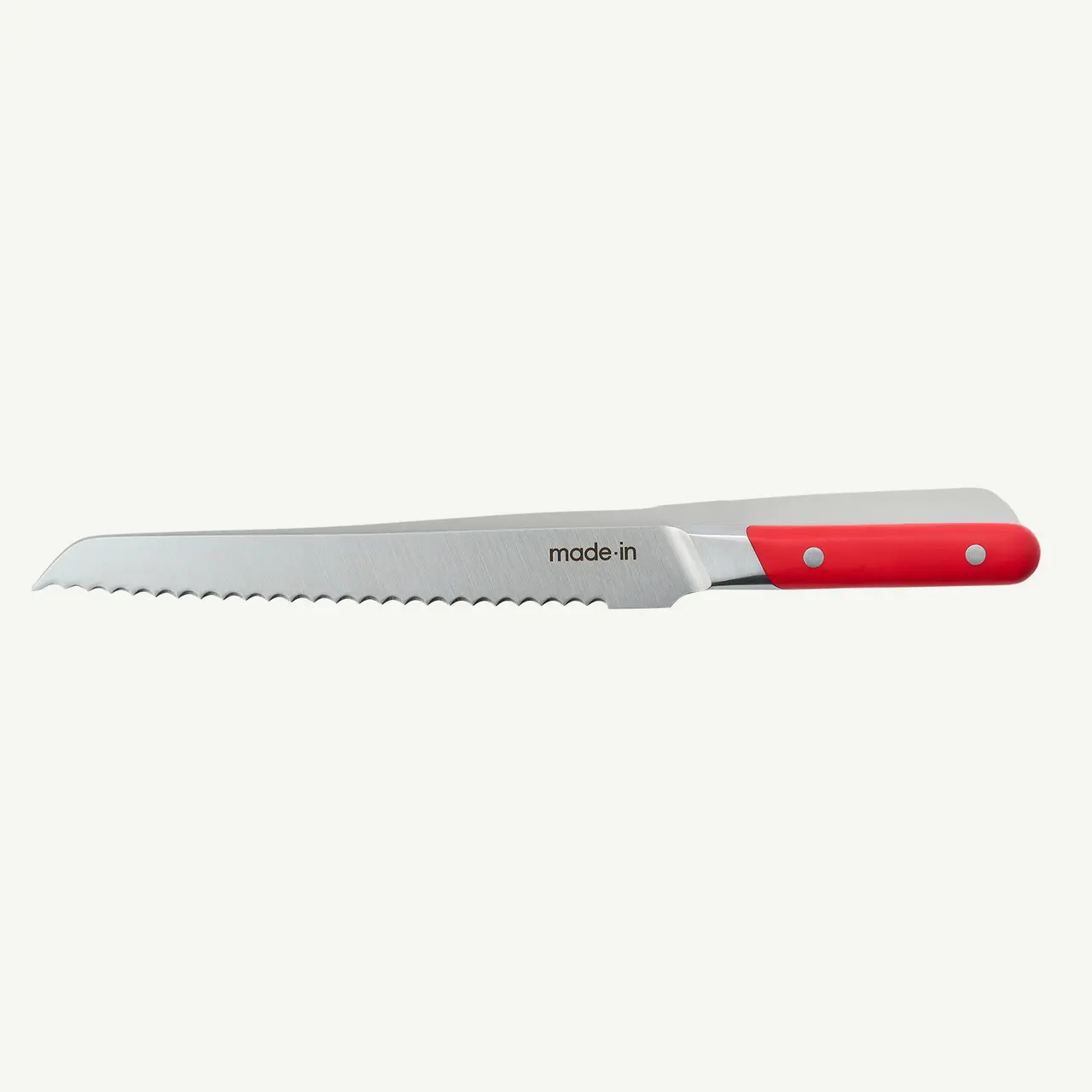 A serrated bread knife with a red handle is displayed against a white background.