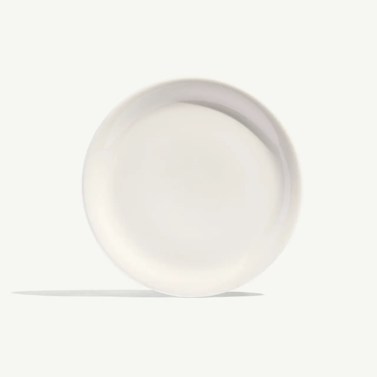 A solitary white plate is centered on a plain background, showcasing its simple round design.