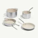 A set of four cookware pieces, including two pots and two pans, with a sleek silver exterior and cream-colored interiors.